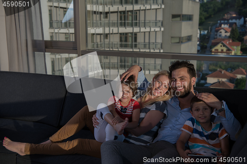 Image of happy young couple spending time with kids at home