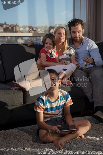 Image of happy young couple spending time with kids at home