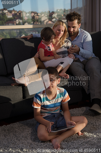 Image of happy young couple spending time with kids at home