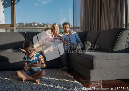 Image of happy young couple spending time with kids at home