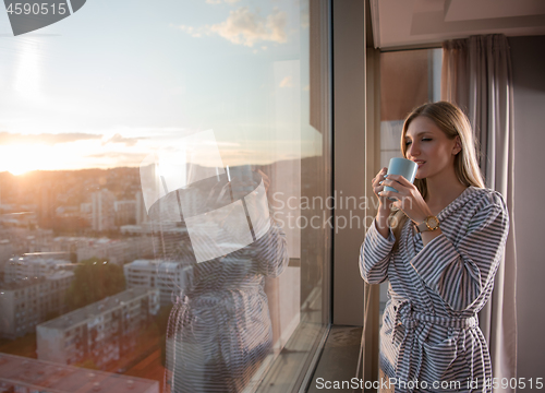 Image of young woman enjoying evening coffee by the window