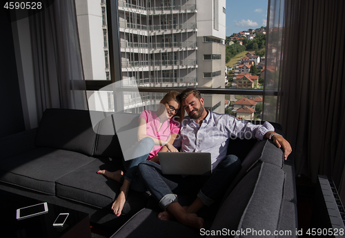 Image of couple relaxing at  home using laptop computers