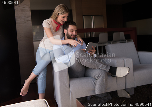 Image of couple relaxing at  home with tablet computers