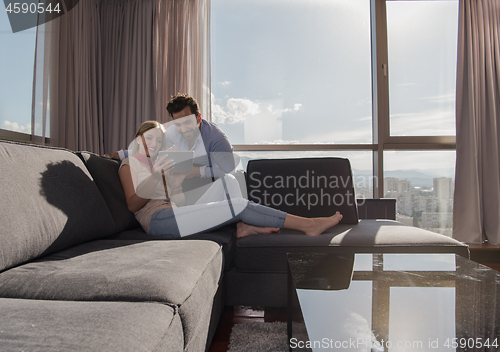 Image of couple relaxing at  home using tablet computer