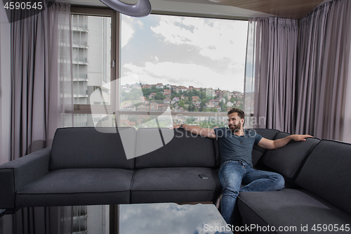 Image of young casual man using a mobile phone at home