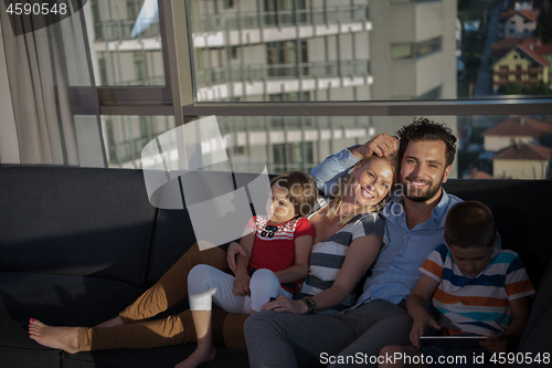 Image of happy young couple spending time with kids at home