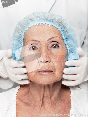 Image of surgeon doing skin check on mid age woman before plastic surgery