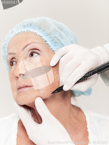 Image of surgeon doing skin check on mid age woman before plastic surgery