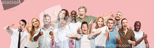 Image of The happy business women and men standing and smiling against pink background.