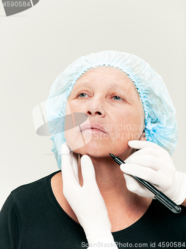 Image of surgeon doing skin check on mid age woman before plastic surgery
