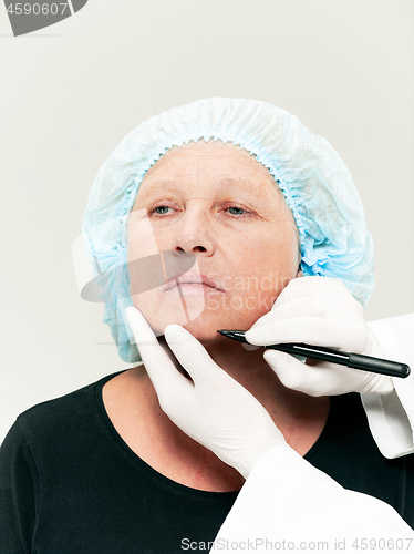 Image of surgeon doing skin check on mid age woman before plastic surgery