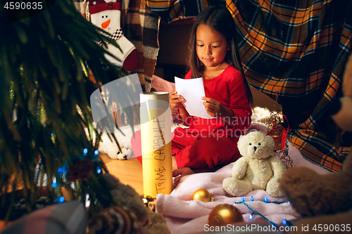 Image of Merry Christmas and Happy Holidays. Cute little child girl writes the letter to Santa Claus near Christmas tree