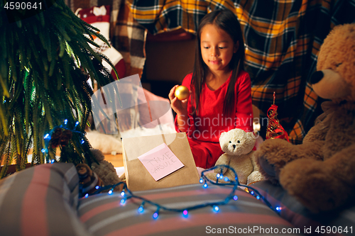 Image of Merry Christmas and Happy Holidays. Cute little child girl writes the letter to Santa Claus near Christmas tree