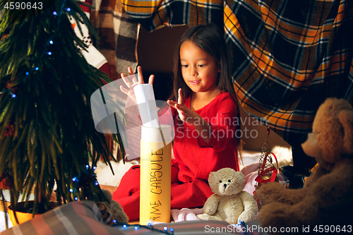 Image of Merry Christmas and Happy Holidays. Cute little child girl writes the letter to Santa Claus near Christmas tree