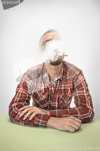 Image of Handsome hipster man smoking cigarette at home. Man looking upwards and enjoying spending free time.