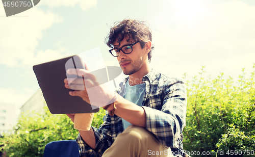 Image of man in glasses with tablet pc on city street