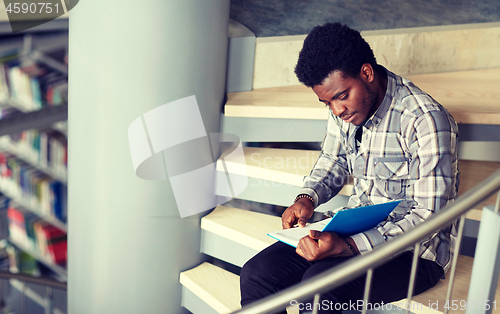 Image of african student boy or man reading book at library