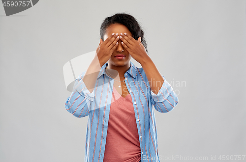Image of african american woman with eyes closed by hands