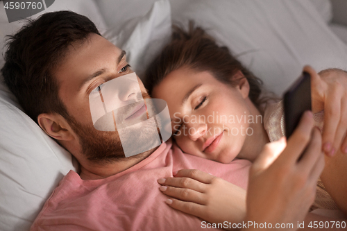 Image of man using smartphone while girlfriend is sleeping