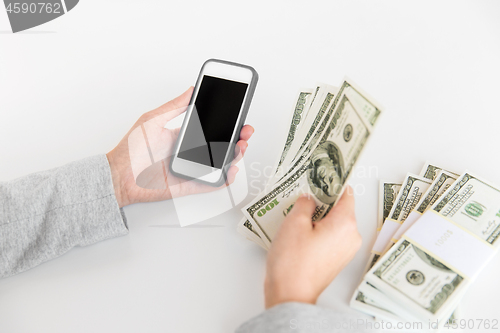 Image of close up of hands with smartphone and dollar money