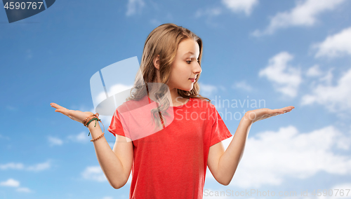 Image of smiling teenage girl holding empty hand over sky