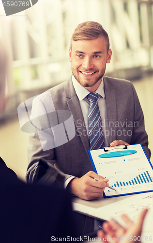 Image of smiling businessman with graph at business meeting