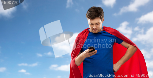 Image of man in red superhero cape with smartphone over sky