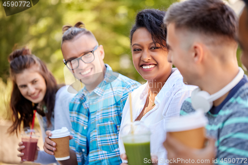 Image of friends drinking coffee and juice talking in park