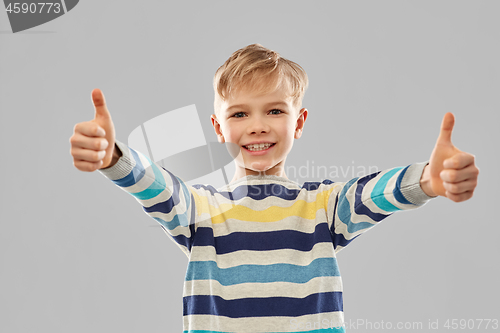 Image of smiling boy in striped pullover showing thumbs up