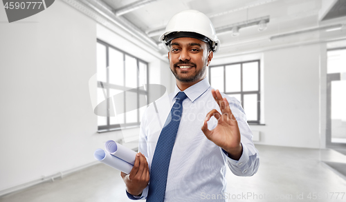 Image of architect in helmet with blueprints showing ok