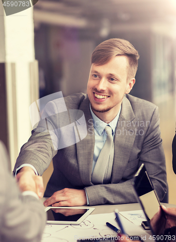 Image of smiling businessman making handshake at office