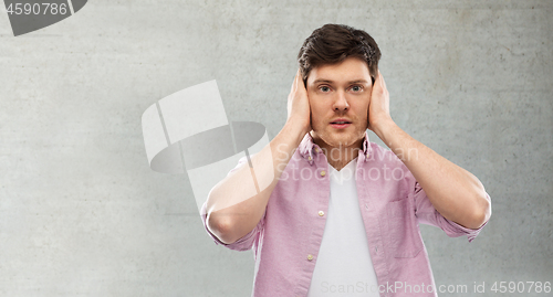 Image of man closing ears by hands over gray concrete wall