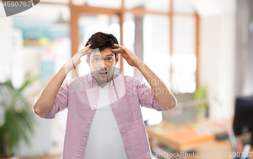 Image of man touching his head over office room