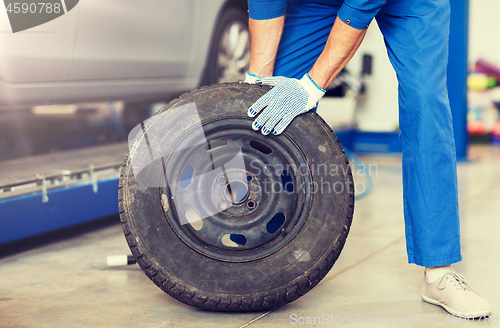 Image of mechanic with wheel tire at car workshop