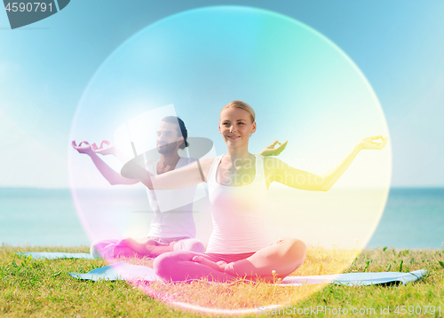 Image of couple doing yoga in lotus pose with rainbow aura