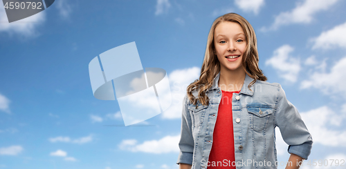 Image of smiling teenage girl in denim jacket over sky