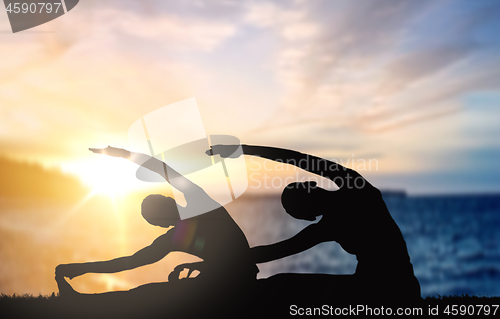 Image of couple doing yoga over sunset sea background