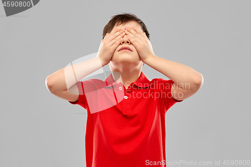 Image of boy in red t-shirt closing his eyes by hands