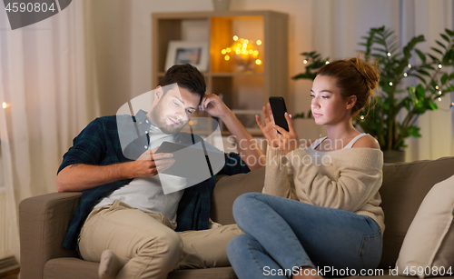 Image of couple with tablet computer and smartphone at home