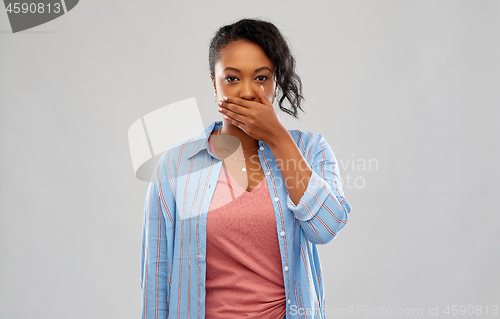Image of shocked african american woman covering her mouth