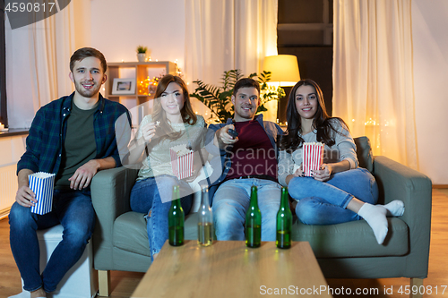 Image of friends with beer and popcorn watching tv at home