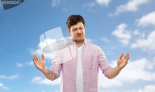 Image of doubting man showing size of something over sky