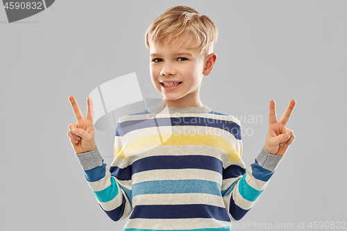 Image of smiling boy in striped pullover showing peace