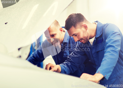 Image of mechanic men with wrench repairing car at workshop