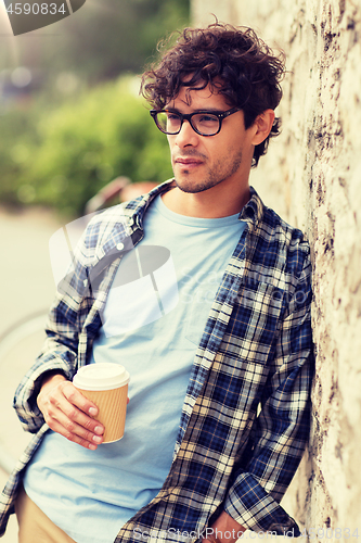 Image of man in eyeglasses drinking coffee over street wall