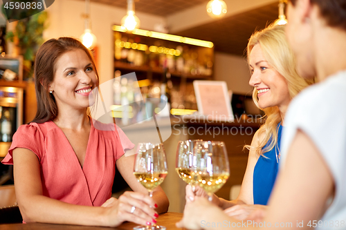 Image of happy women drinking wine at bar or restaurant