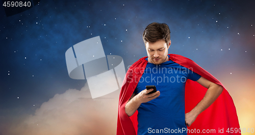 Image of young man in red superhero cape using smartphone