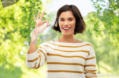 Image of happy smiling woman in striped pullover showing ok