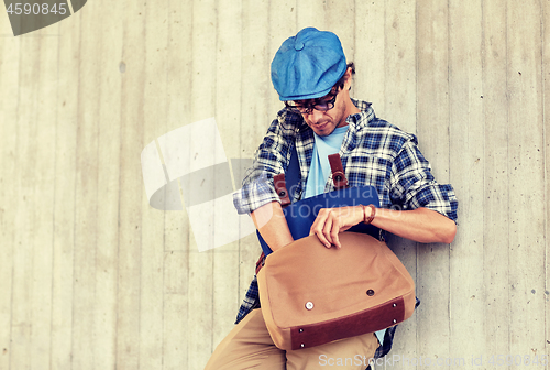 Image of hipster man looking for something in his bag