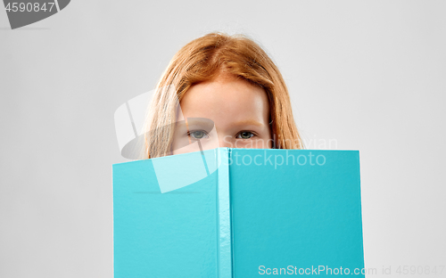 Image of smiling red haired girl reading book